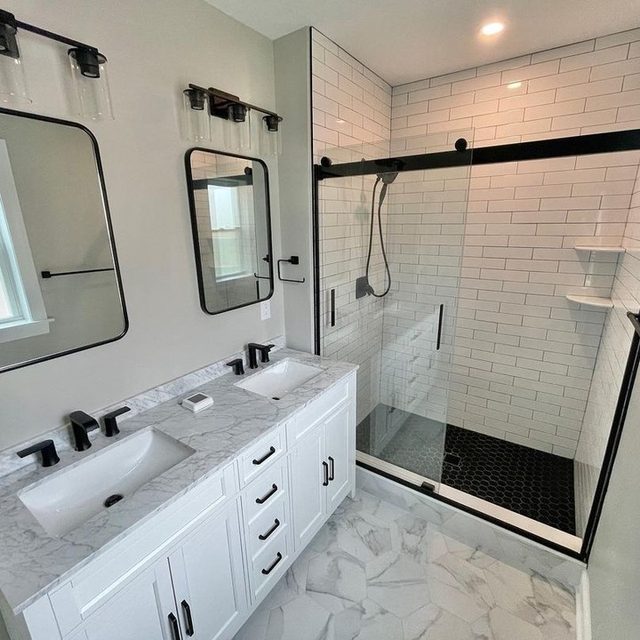 Renovated bathroom with white subway tile shower, black-framed glass door and marble-look floor tile